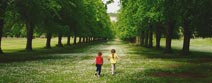 Two children running through park