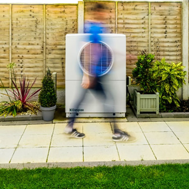 Blurry image of a person moving in front of heat pump system outside a house.