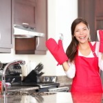 Woman wearing oven gloves standing beside an oven