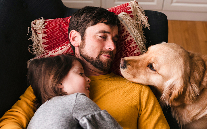 Daughter and dog lying on father, a sweet family scene