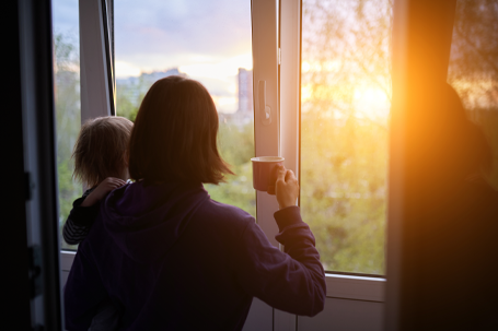 A mother and baby watching sun out of a window