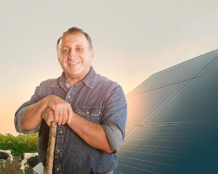 Smiling man in front of a backdrop of solar panels on a farm